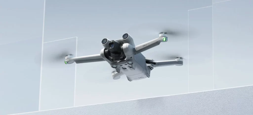 DJI Mini 3 Pro drone repülés közben szürke háttér előtt