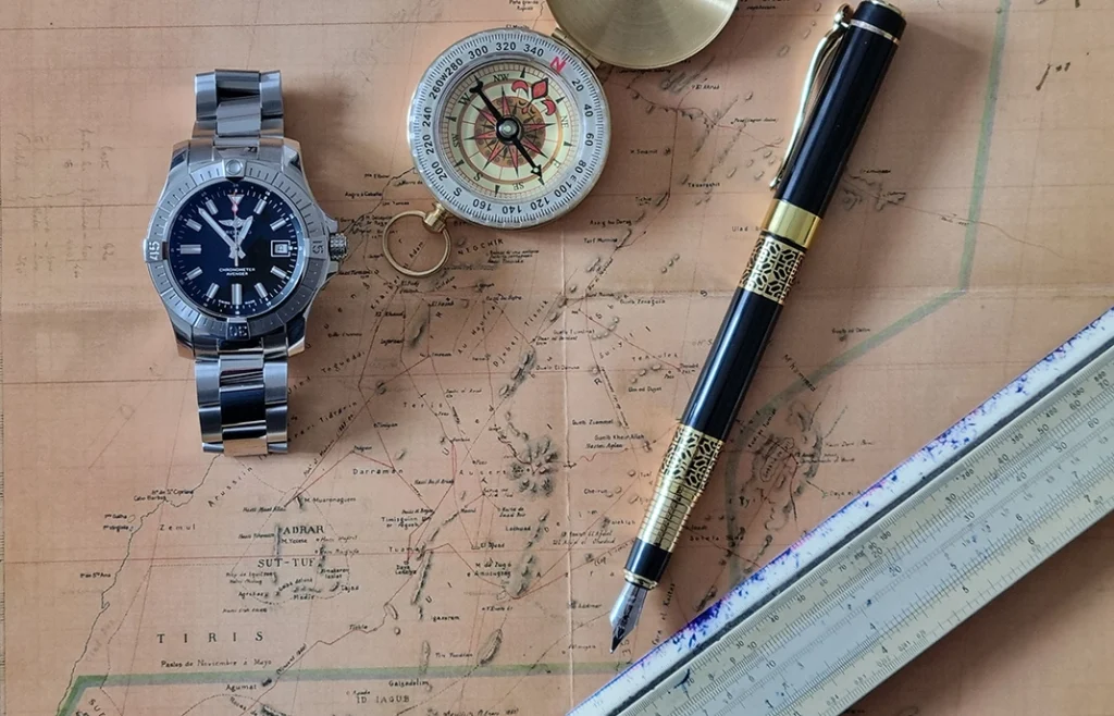 Breitling Avenger látható egy archive térképen, iránytű, töltőtoll és logarléc társaságában.