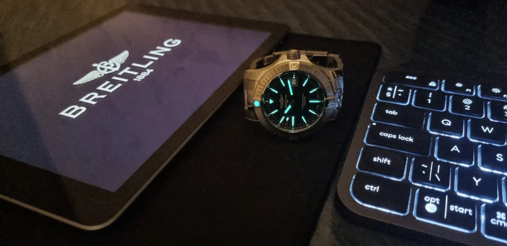 Breitling Avenger sötétben világít egy ipad és egy billentyűzet mellett.