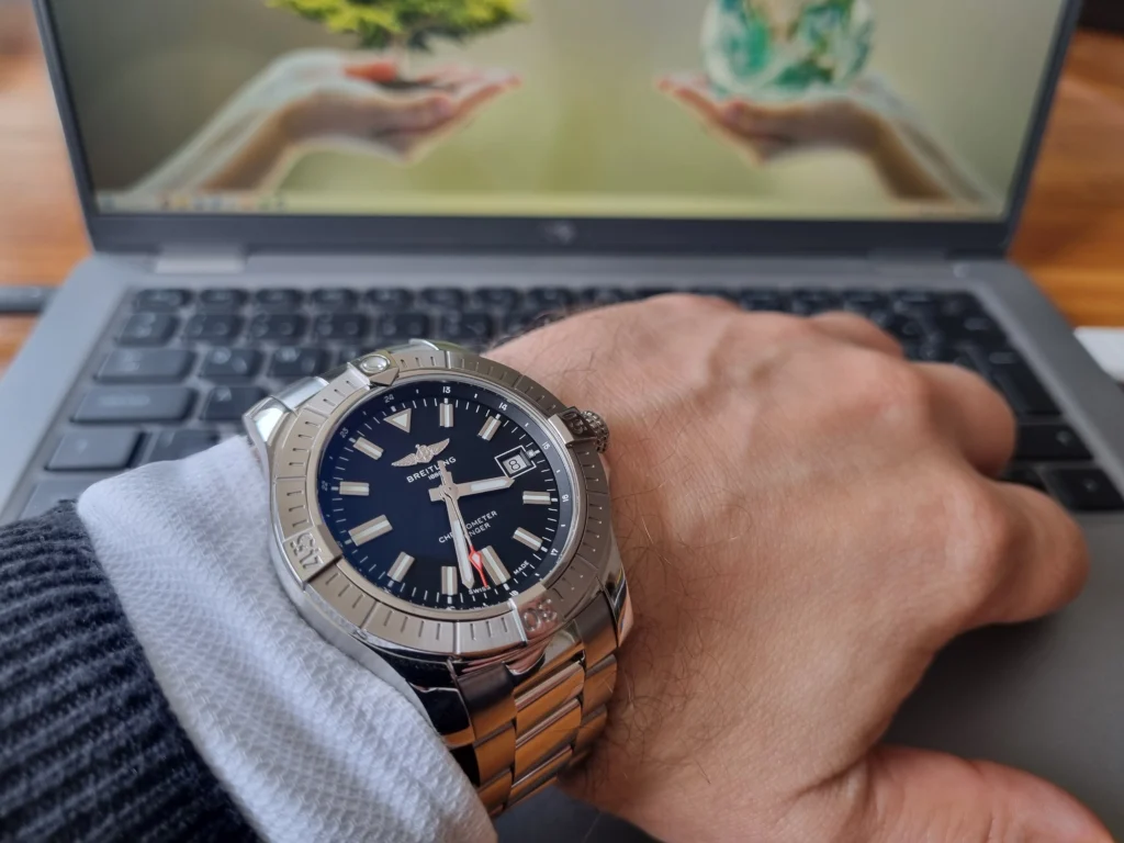 Breitling Avenger csuklón, kék ing és pulóver alól kandikál ki.
